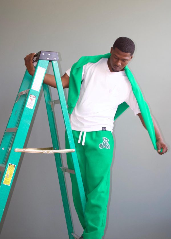 Model wears green stacked joggers white neck tee and green crewneck